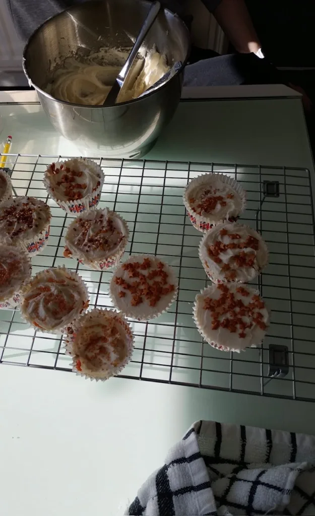 Freshly baked cupcakes topped with colourful sprinkles on a cooling rack.