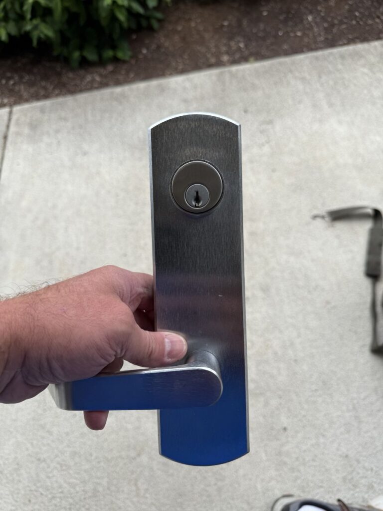 A locksmith removes and rekeys a commercial exit lever trim