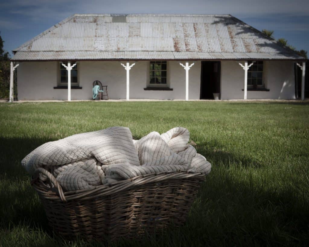 A historic New Zealand Cottage with Premium Cotton and Linen products from The Ottoman Collection in the foreground