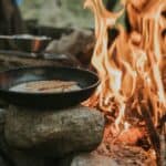 something being cooked on cookware on campfire
