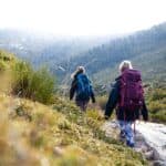 a couple of people hiking downhill with backpacks on