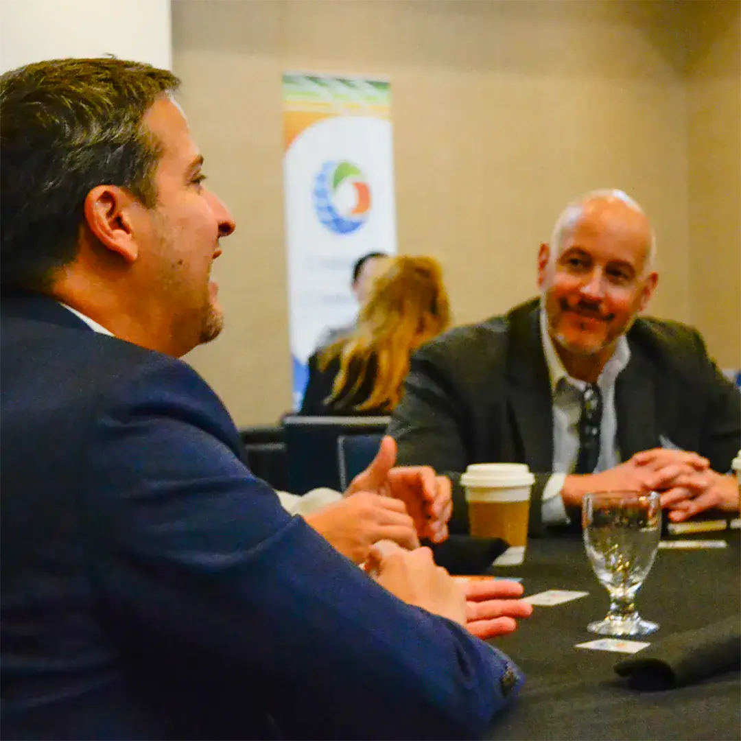 Two men engaged in conversation while seated at a table.