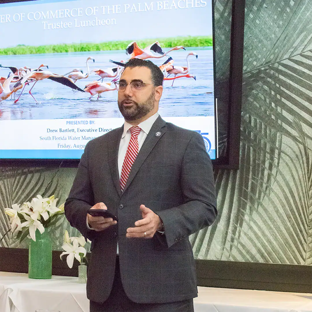 Man in a suit and tie stands in front of a screen.