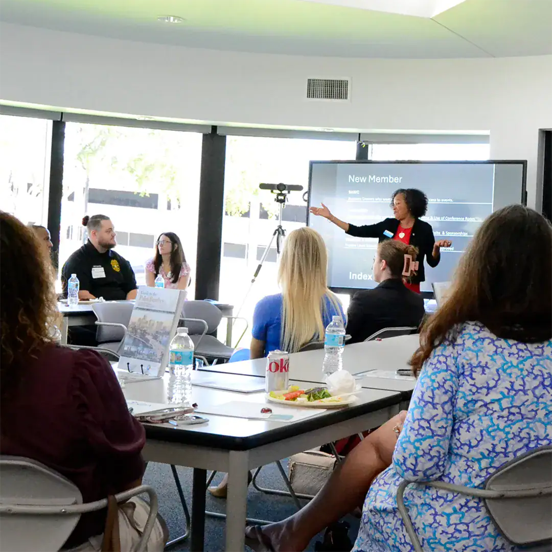 Woman addresses a group, sharing information during a presentation with visual support.