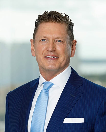 Businessman in a blue suit smiling in an office setting.