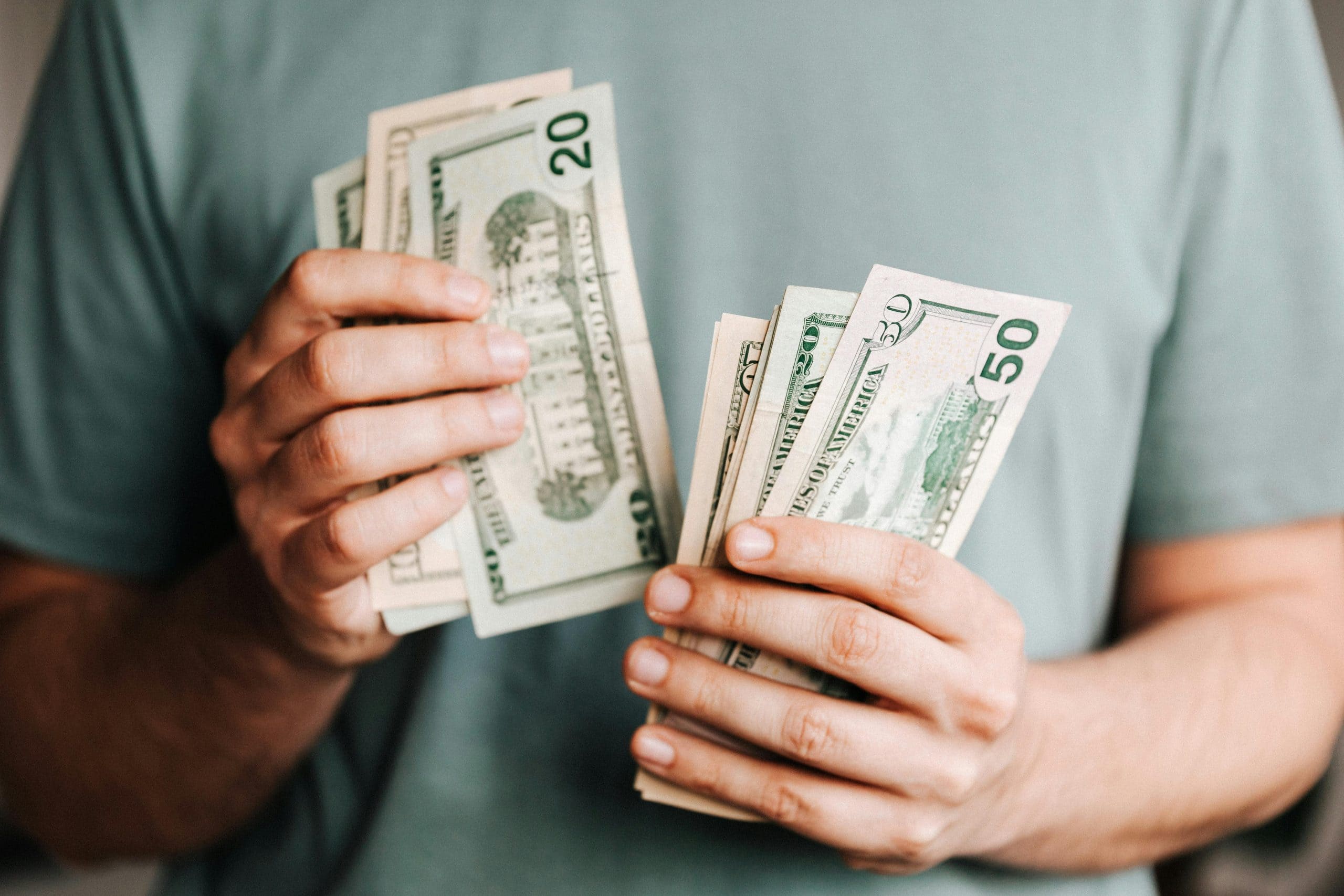 Hands holding multiple bills such as 20s and 10s, counting