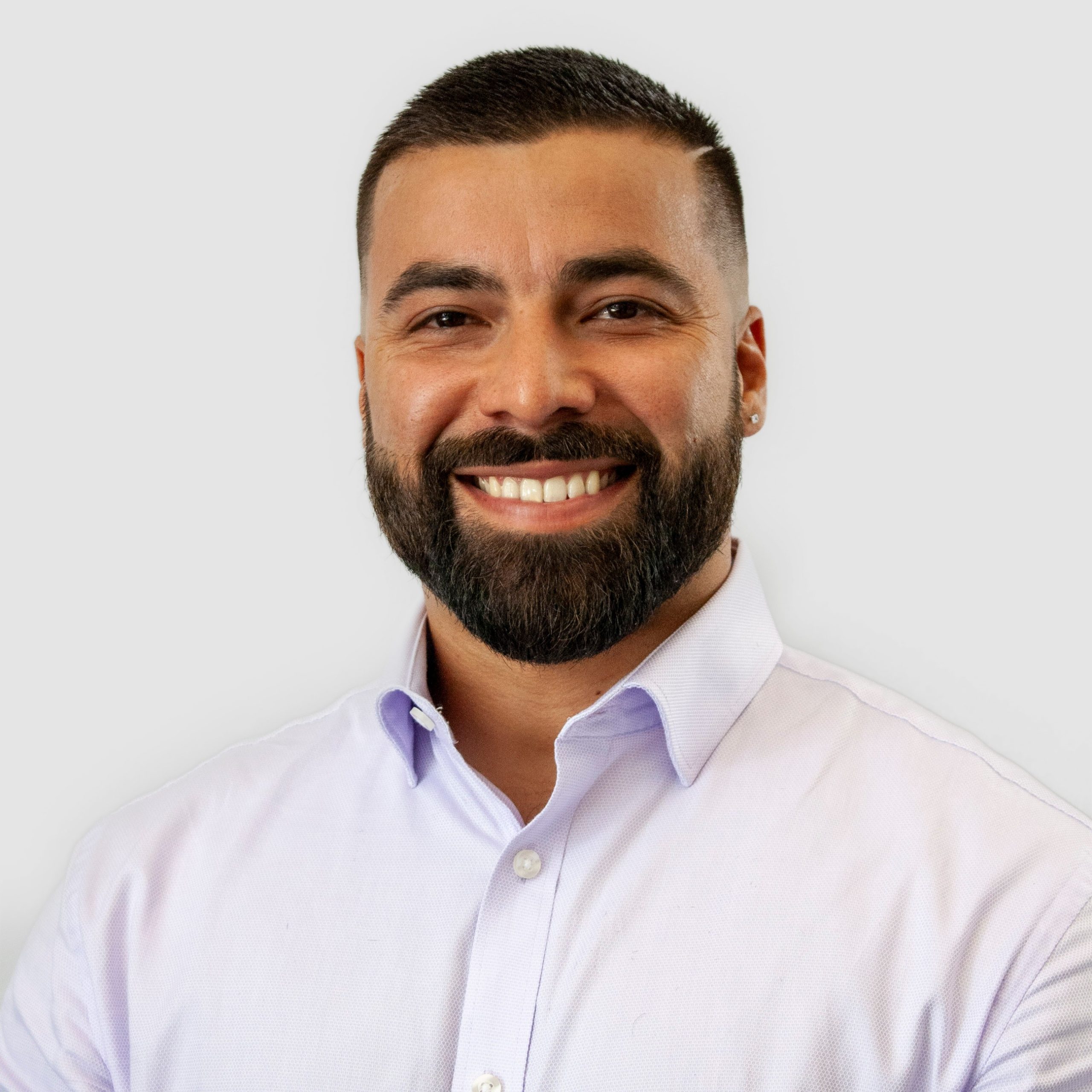 Man smiling with a beard and short hair, wearing a white dress shirt.