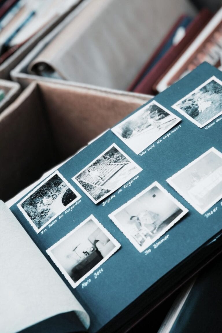 Scrapbook that is open to a blue page with black and white photos on it. Boxes of photo albums are in the background.