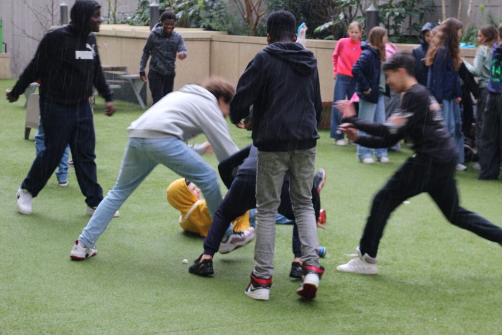 Group of young boys engaging in rough and tumble play with hand-knit anti-stress balls at BioBeo Festival"