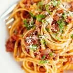 linguine tossed with ragu bolognese in a white bowl with a fork