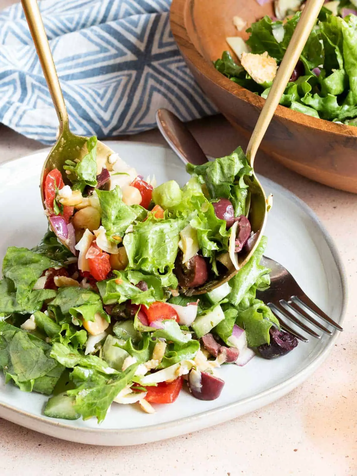 Loaded Greek salad being served on a plate using salad servers.