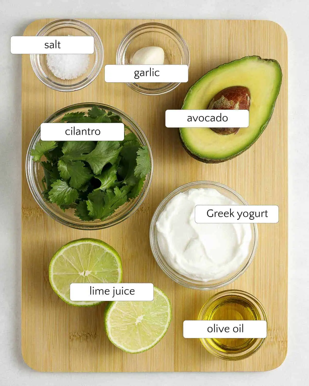 Ingredients for cilantro avocado dressing include salt, a clove of garlic, half an avocado, fresh cilantro, Greek yogurt, lime juice, and olive oil