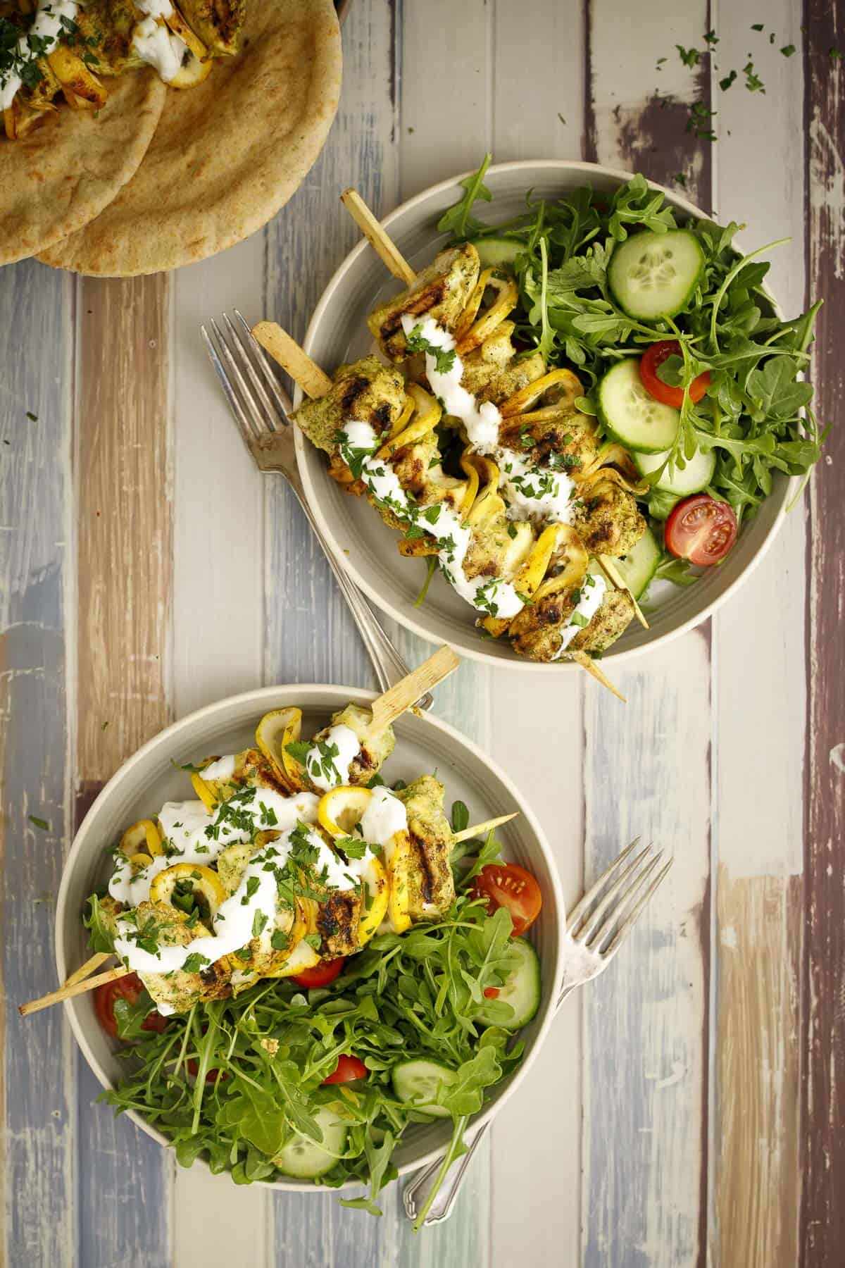 grilled halibut skewers are plated on two plates with salad