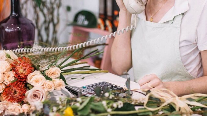 cheerful-woman-speaking-phone-shop