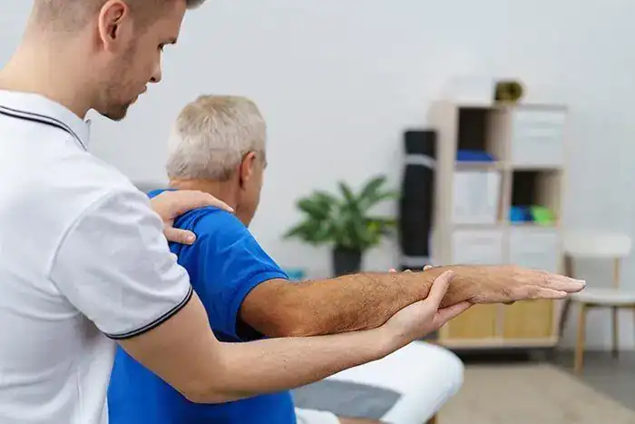 Physio-medicine London - Physiotherapist assisting elderly patient with shoulder stretch.