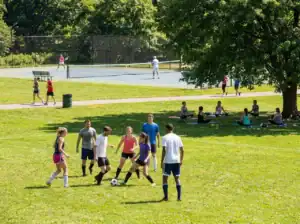 Football game in a park with players enjoying outdoor exercise.