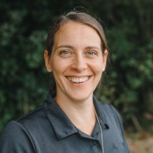 Friendly physiotherapist smiling outdoors at CAREfirst clinic in New Zealand.