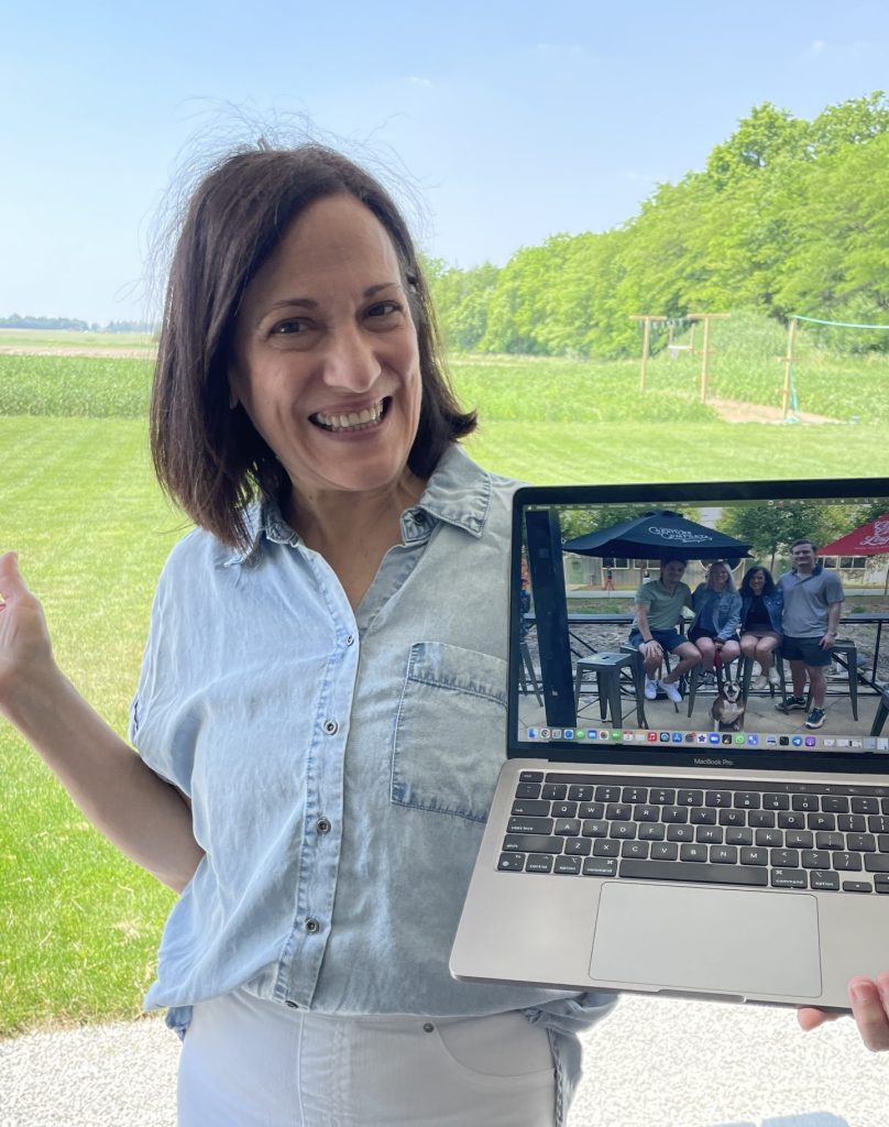 a smiling teacher holding up her laptop with a desktop free of clutter