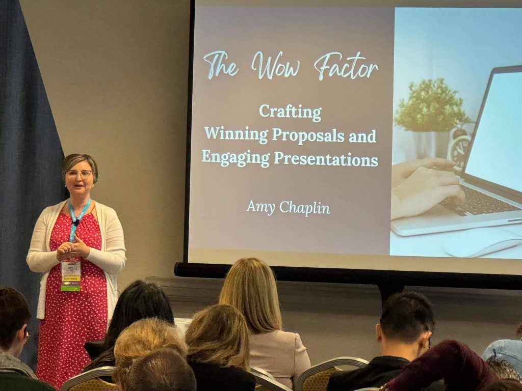 Amy speaking to an audience with a presentation behind her