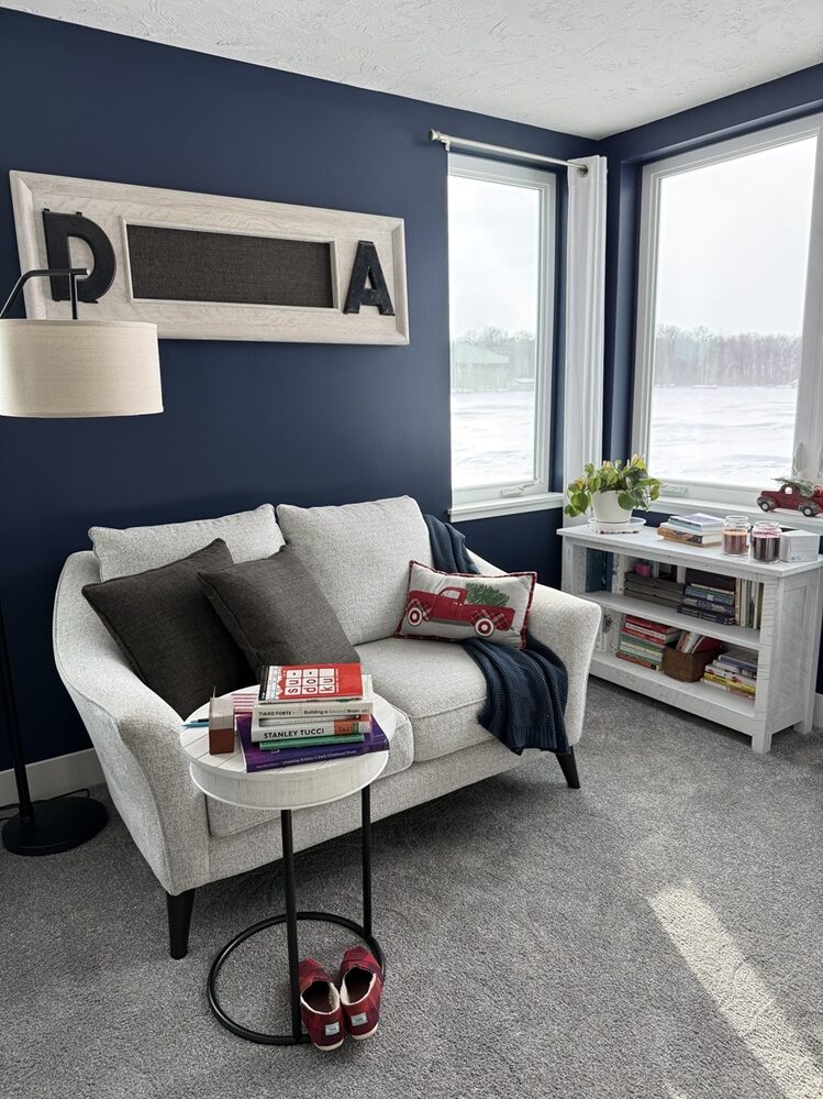 my cozy reading space in my bedroom with a loveseat, bookshelf, small portable side table, and an overhead lamp