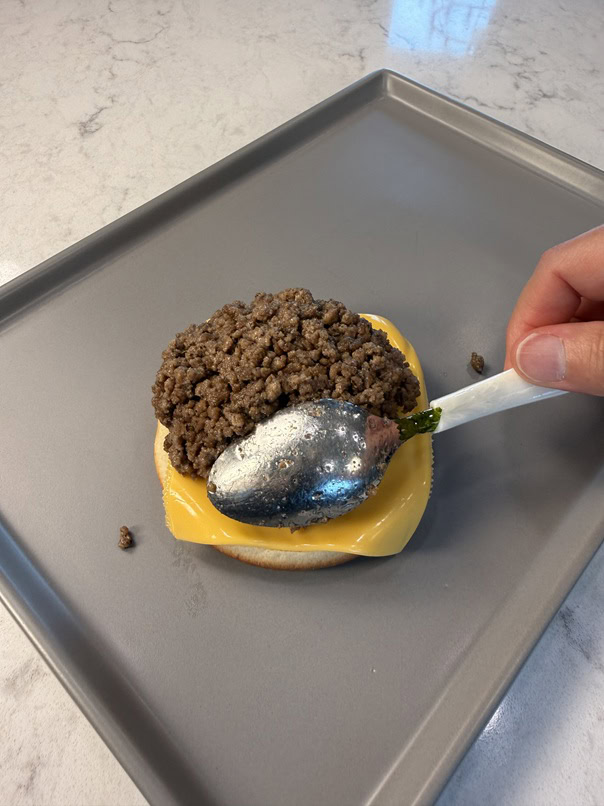 spreading meat on bun with a spoon