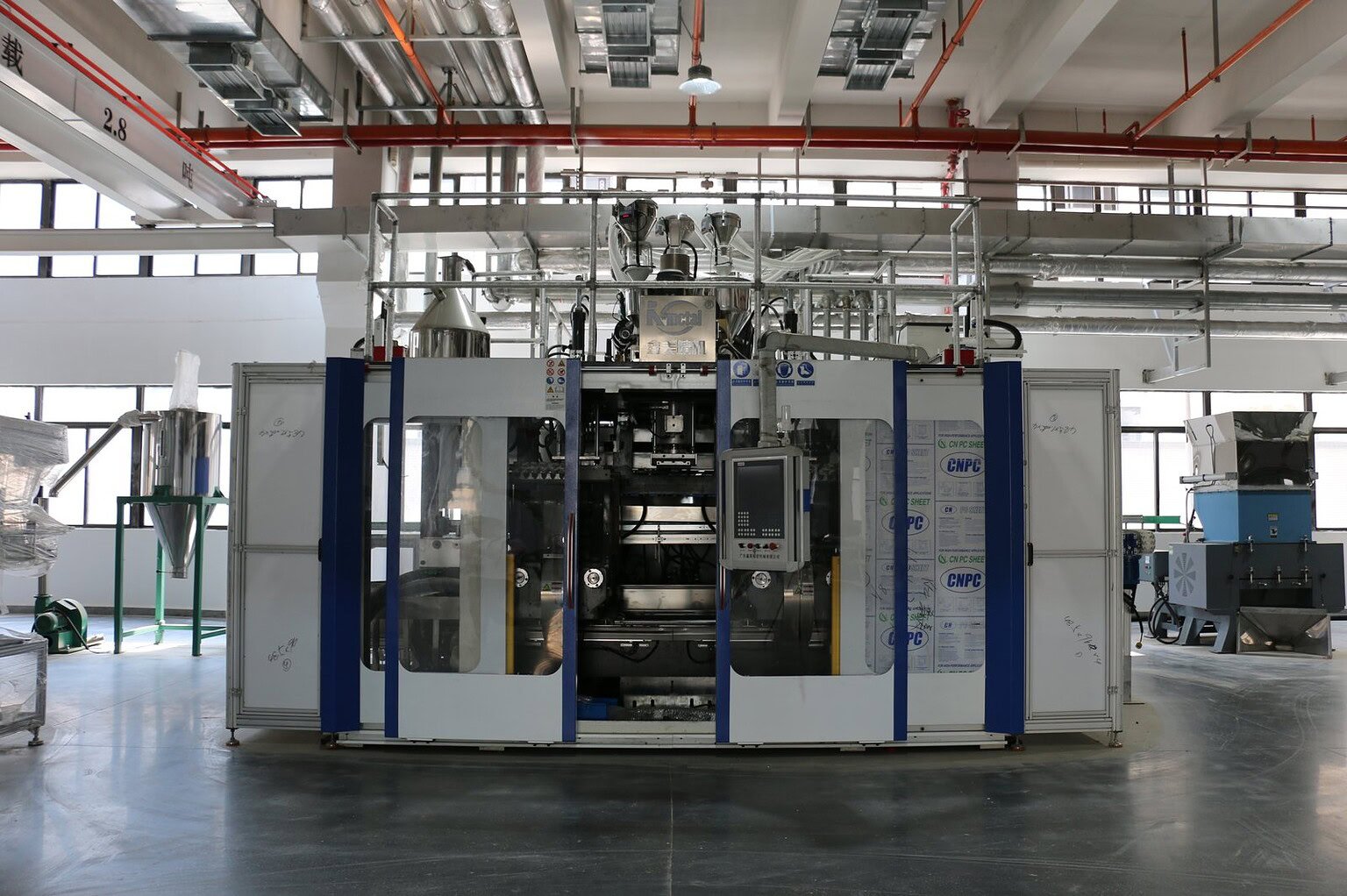 Industrial bottle manufacturing machine in a modern factory setting.