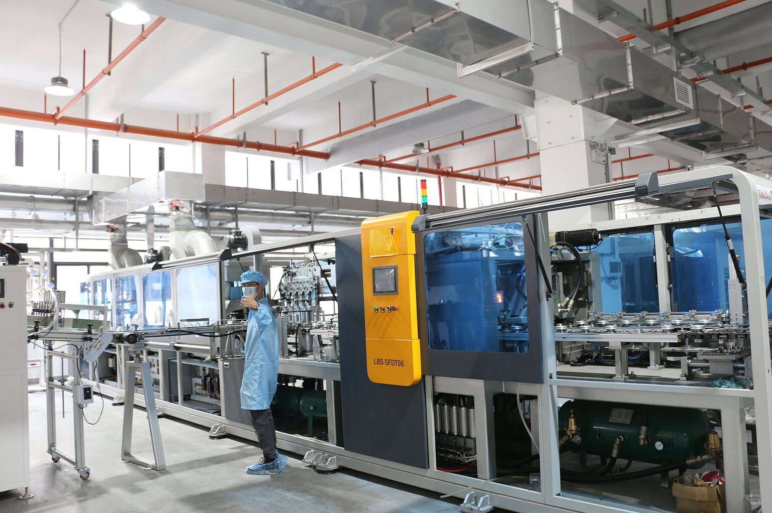 Modern glass and plastic bottle manufacturing machinery in a clean factory setting.