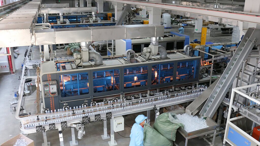 High-speed plastic bottle manufacturing machine in a factory setting.