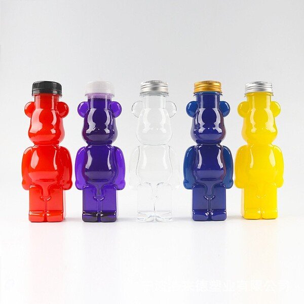 Red, purple, clear, blue, and yellow bear-shaped bottles for juice, made from food-grade plastic, di.