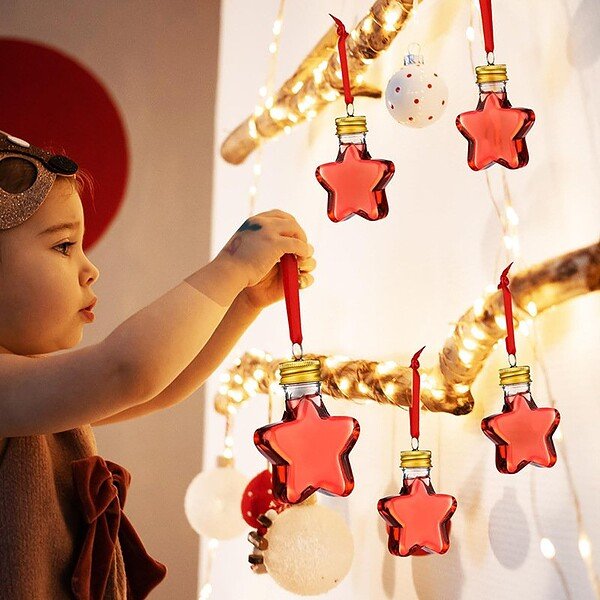 Child decorating with Christmas star-shaped bottles for juice, holiday celebration.