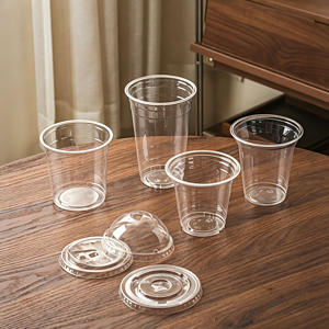 Clear plastic cups with lids on a wooden table, suitable for beverages and takeout.