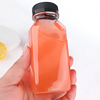 Clear plastic bottle with black cap, hand-held, on white background.