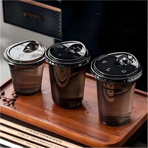 black plastic cups filled with drinks are placed on the bar counter. PET cups are suitable for juice shops, coffee shops, soft drink shops, and bubble tea shops.