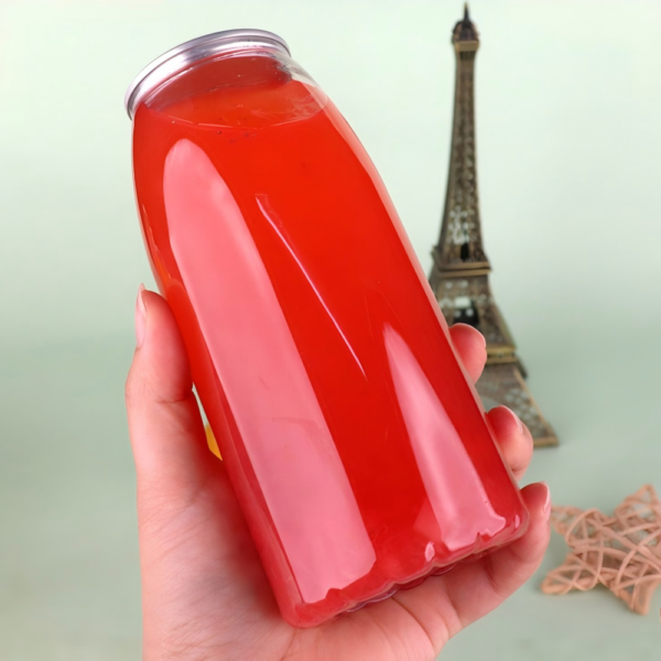 Red beverage in a clear plastic bottle with a miniature Eiffel Tower in background.