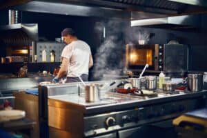 a professional kitchen with chefs working, highlighting the importance of air quality and hygiene in hospitality kitchens, enhanced by plasma cleaning technology.