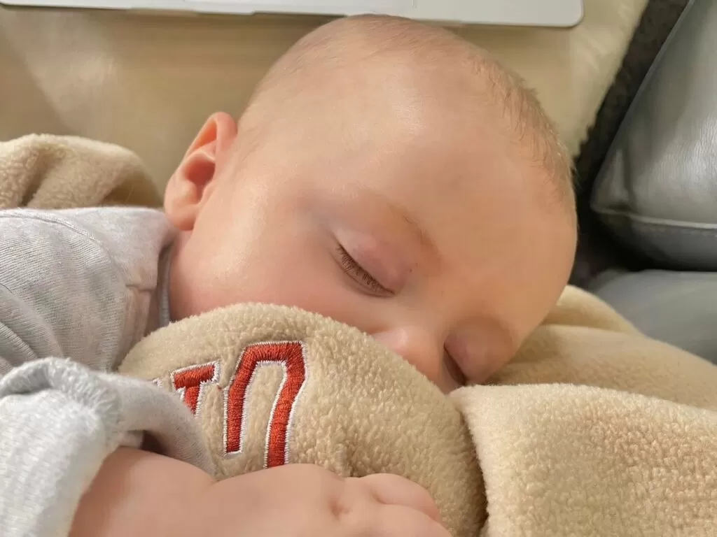 a baby breastfeeding and sleeping in his mother's arms