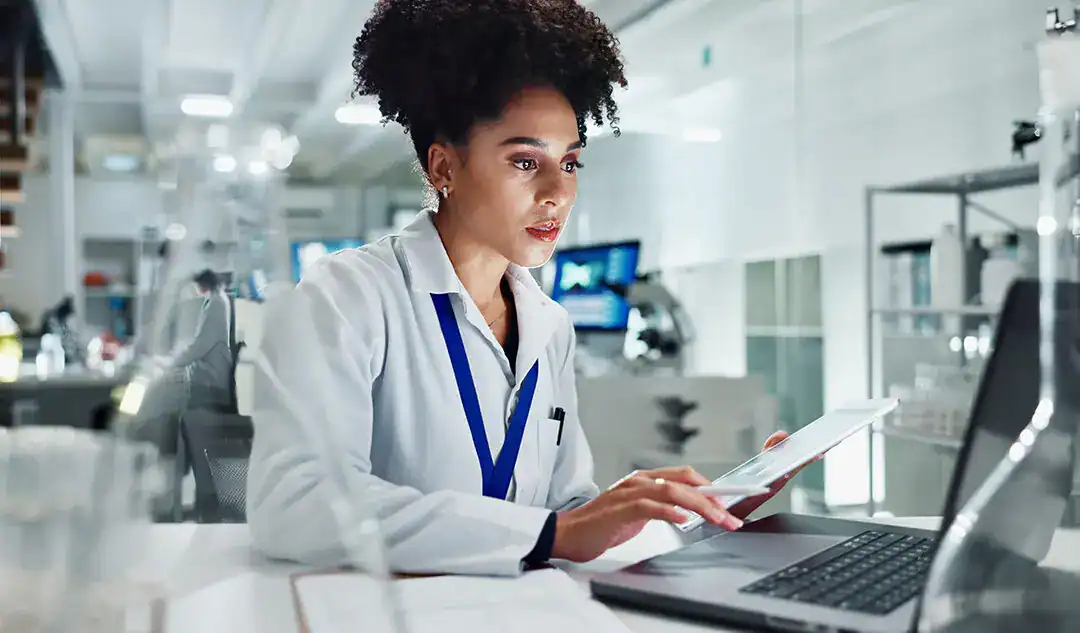 Medical professional analyzing data on a tablet in a hospital setting.
