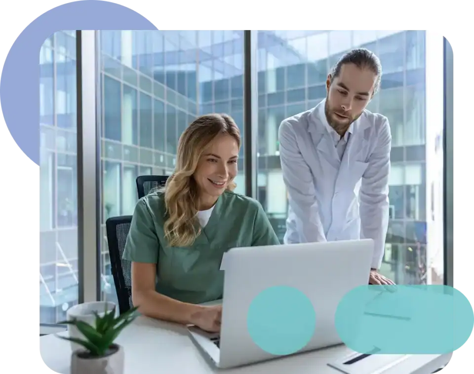 Healthcare professionals discussing patient data on laptop in modern office.