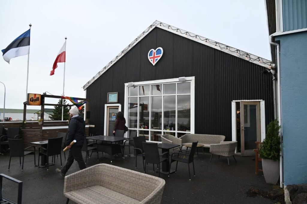 Scenic waterfront café in Húsavík with outdoor seating and Icelandic flags.