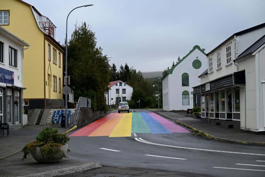 Vibrant rainbow crosswalk in Húsavík, Iceland, blending colorful street art with picturesque town sc.
