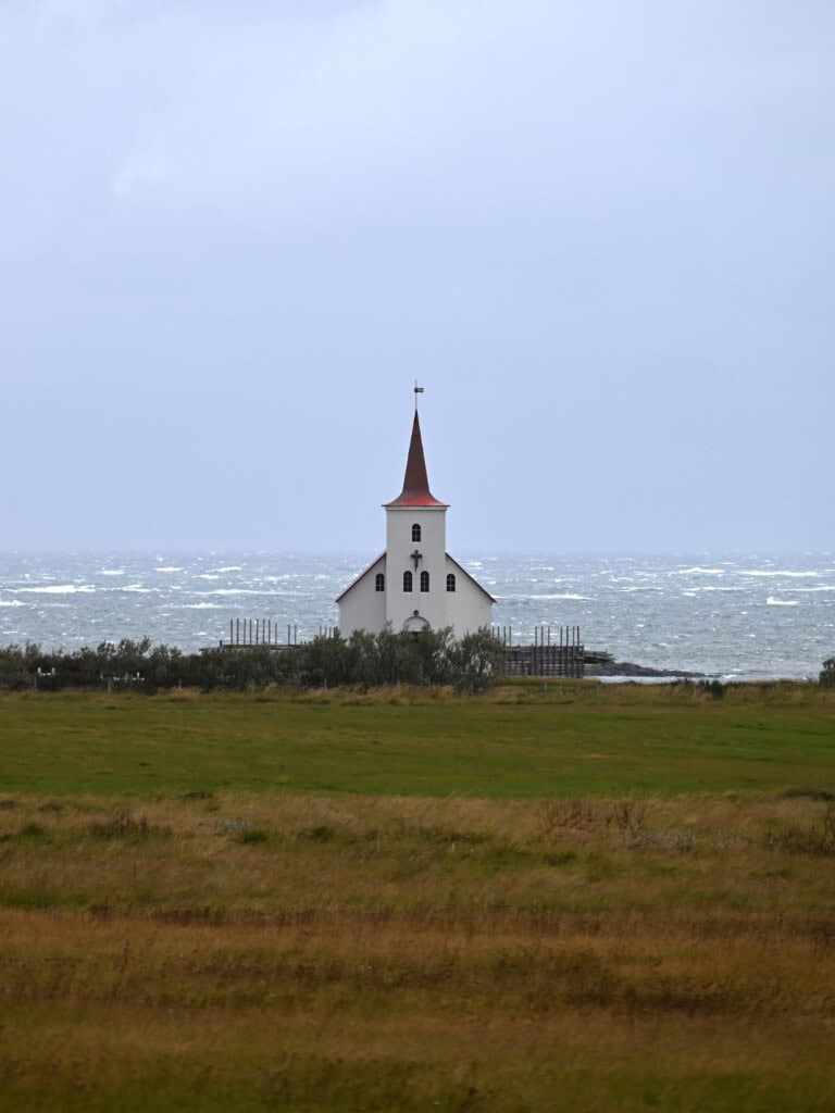 Seaside church with a red steeple overlooking the ocean in Westfjords, Iceland.