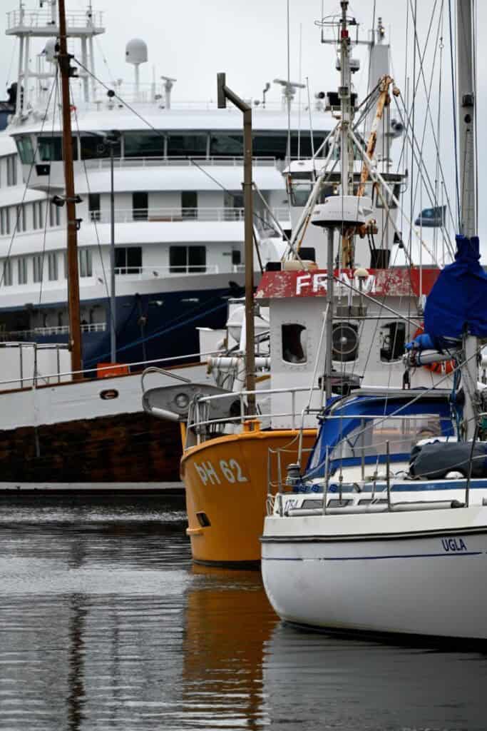 Maritime boats in Húsavík harbor with Hvitserkur in the background.