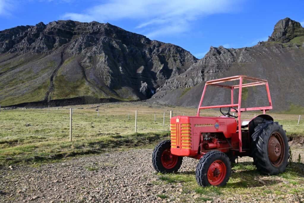 Old red tractor on the Snæfellsnes Peninsula with rugged mountains in the background.