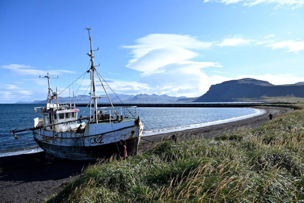 Old fishing boat on the shore of Snæfellsnes Peninsula, Iceland, with mountains and ocean in the bac.