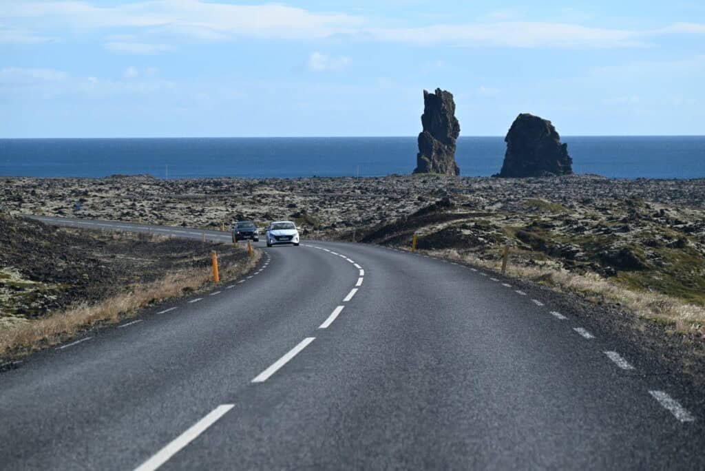Scenic drive along the coast of Snæfellsnes Peninsula with sea stacks in the background.