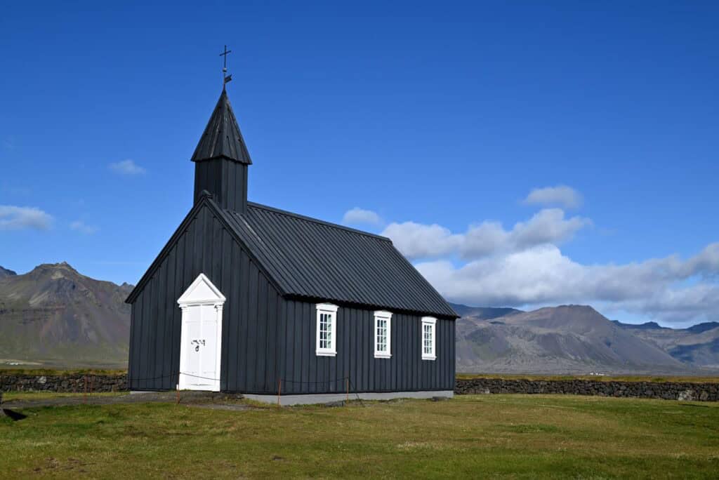 Historic black church on the Snæfellsnes Peninsula, Iceland, with scenic mountain views.