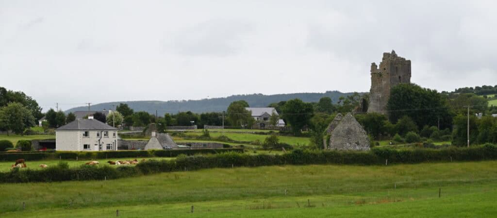 Cashel Castle ruins with lush green Irish landscape and rural homes.