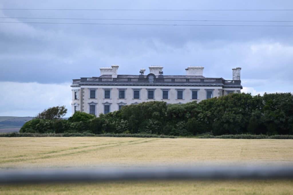 Castle on the Irish Copper Coast with lush greenery and cloudy sky backdrop.