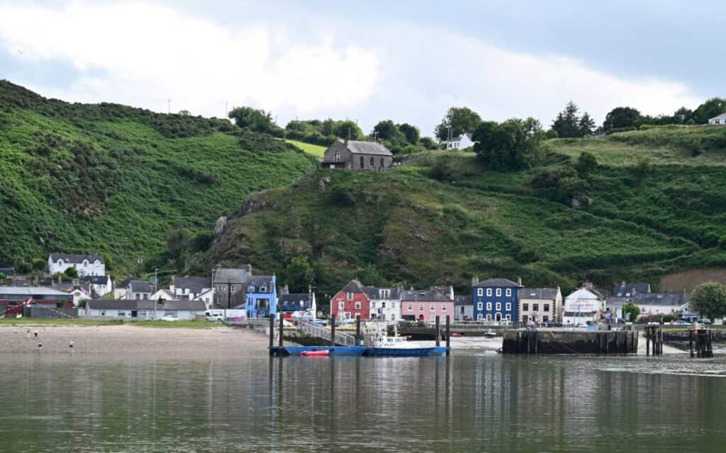 Vibrant Irish village along the Copper Coast with colorful houses and scenic green hills in County C.