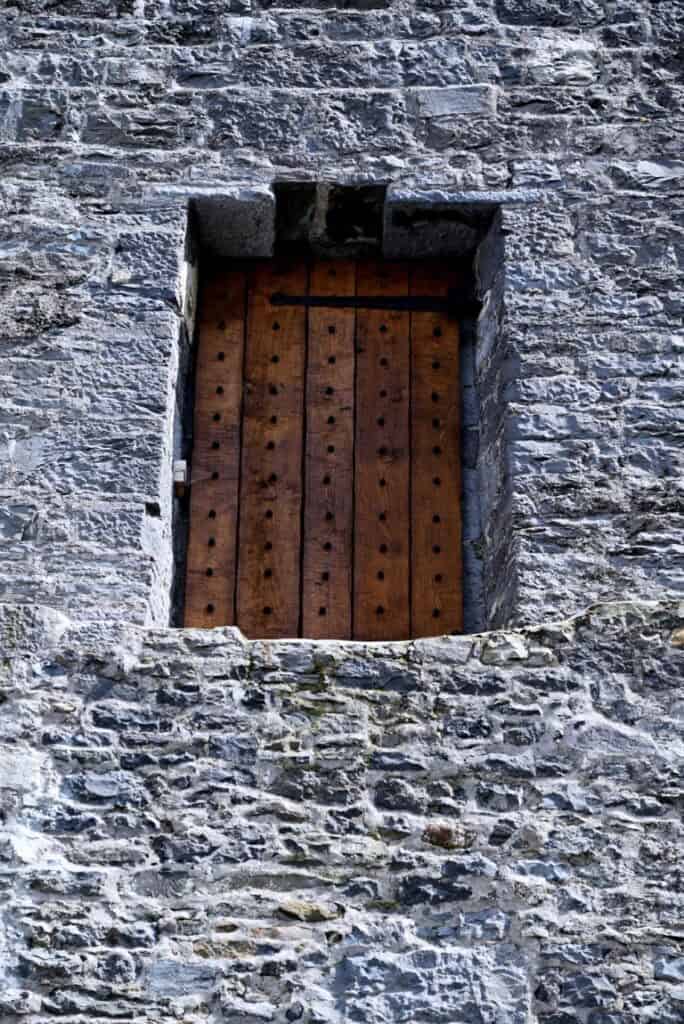 Stone wall with a rustic wooden window in Dingle, Ireland.